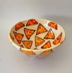 an orange and white bowl with slices of pizza printed on the side, sitting on a table