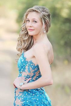 a beautiful young woman in a blue dress posing for a photo with her hands on her hips