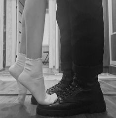 a man and woman standing next to each other on a hard wood floor in black and white