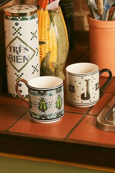 two coffee mugs sitting on top of a kitchen counter