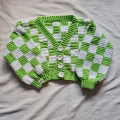 a green and white sweater laying on top of a bed