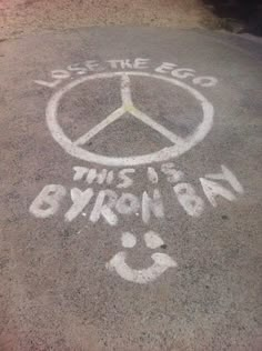 a peace sign painted on the ground with words written in white chalk and black marker