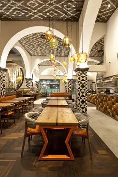 the interior of a restaurant with wooden tables and chairs, hanging lights and patterned walls