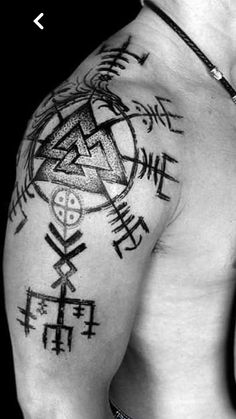 black and white photo of a man's chest with tattoos on it, including symbols