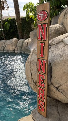 a wooden sign that says minnesota on it next to a pool with rocks and trees