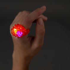 a hand is holding a glowing ring with red and yellow lights on it's fingers