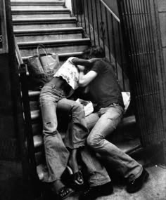 black and white photograph of two people sleeping on stairs