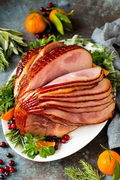 glazed spiral ham on a plate with cranberries and oranges