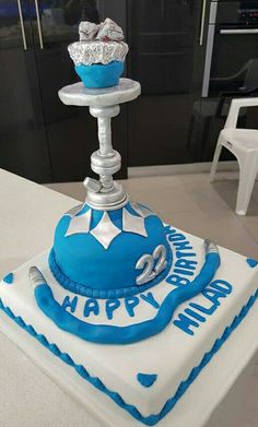 a blue and white cake with a cupcake on top