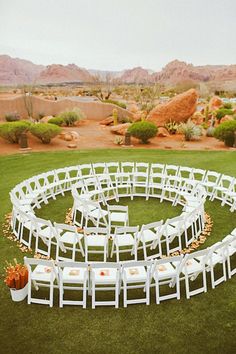 an outdoor ceremony setting with white chairs and flowers