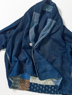 an old jean jacket with patchwork on the front and back, sitting on a white surface