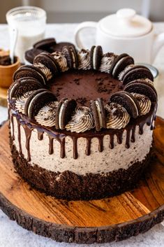 a chocolate cake with oreo cookies and cream drizzled over it on a wooden platter