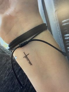 a woman's arm with a cross tattoo on the left side of her wrist