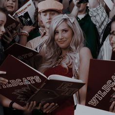 a group of people standing around each other holding books