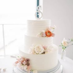 a three tiered white cake with flowers on the side and number eight on top