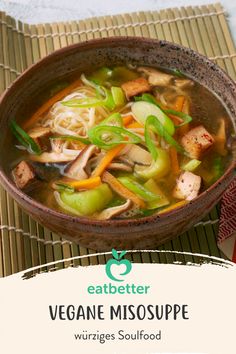 a bowl of vegetable miso soup on top of a mat