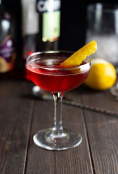 a red drink with a lemon wedge on the rim