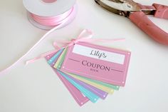 pink ribbon, scissors and other crafting supplies on a table with labels for coupons