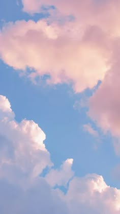 the plane is flying high in the sky with some clouds behind it and blue skies above