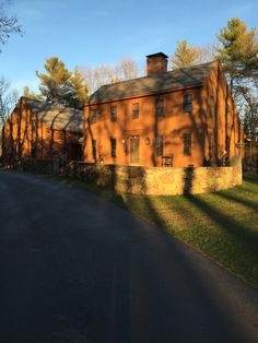 an old brick building sitting on the side of a road in front of some trees