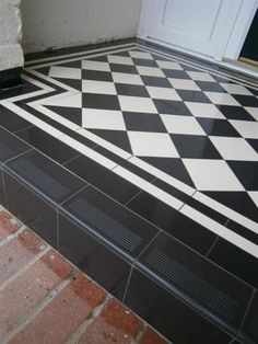 a black and white checkerboard floor in front of a door on a brick walkway