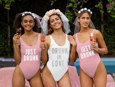 three women in pink swimsuits standing next to each other and holding wine glasses