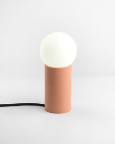 a light that is on top of a white floor lamp with a black cord in front of it