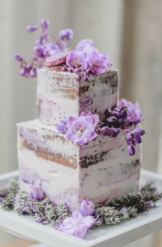 a three tiered cake with purple flowers on top