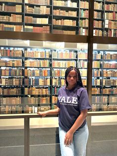 a woman standing in front of a library filled with books