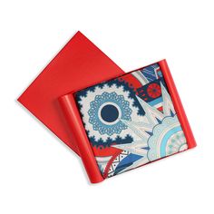 two red napkins with blue and white designs on them are sitting next to each other