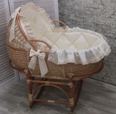 a wicker baby bassinet with white ruffles and bows on it