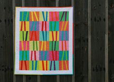 a colorful quilt hanging on a wooden fence