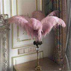 a table with a lamp and some pink feathers on it