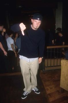 a man in black shirt and khaki pants standing on wooden floor with other people