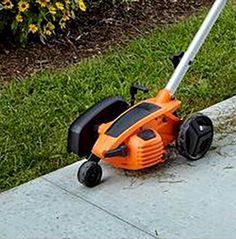 an orange lawn mower sitting on top of a sidewalk