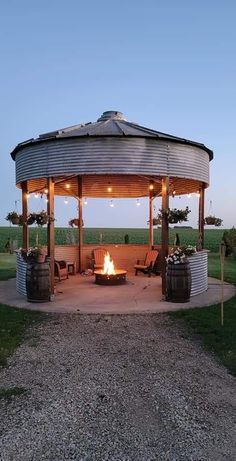 a fire pit in the middle of a field with barrels around it and lights on