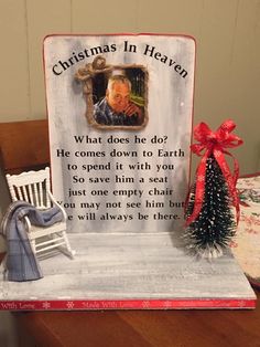 a christmas card sitting on top of a wooden table next to a chair and tree