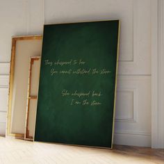 there is a green chalkboard with gold writing on it next to an empty frame