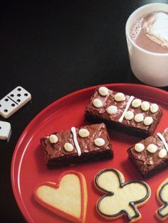 a red plate topped with brownies covered in icing and marshmallows