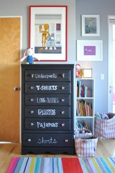 a black dresser with writing on it in a room next to a bookcase and bookshelf