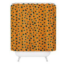 an orange shower curtain with black and green spots on the bottom, in front of a white bathtub