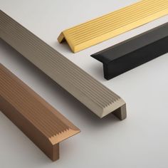 three different types of wooden slats on a white surface, one is yellow and the other two are brown