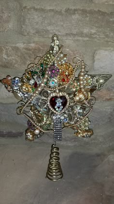 a star shaped brooch sitting on top of a metal stand next to a stone wall