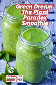 two mason jars filled with green smoothie next to each other on a blue cloth