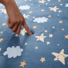 a child's hand pointing at the stars on a blue blanket that has clouds and stars all over it