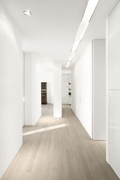 an empty room with white walls and wood floors is seen in this image from the hallway