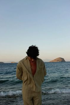 a man standing on top of a beach next to the ocean