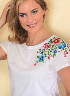 a woman wearing a white shirt with flowers on it