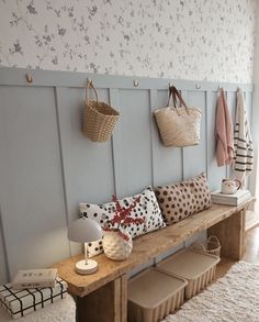 a wooden bench sitting next to a wall with baskets hanging on it's sides