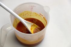 a plastic measuring cup filled with liquid and a spoon